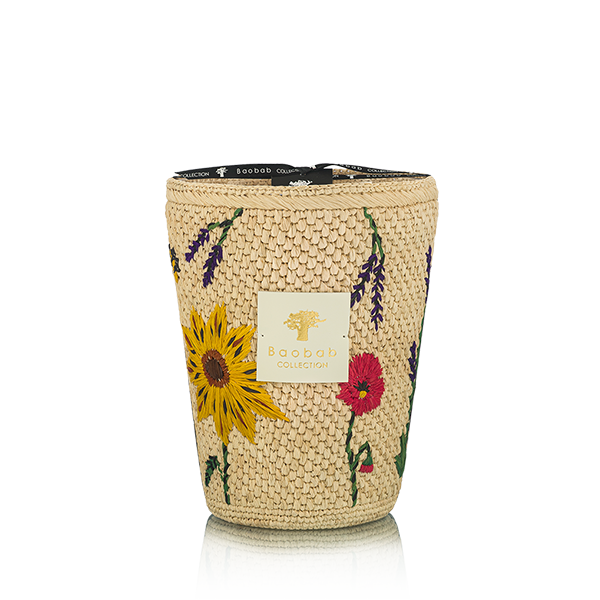 Vela en frasco de fibra tejida beige con flores amarillas y rojas, sobre fondo claro