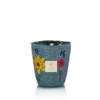 Vela en recipiente tejía azul con flor roja y etiqueta “Baobab Collection”