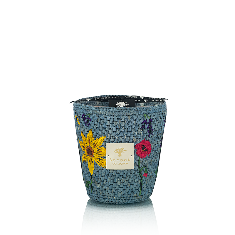 Vela en recipiente tejía azul con flores multicolor y etiqueta frontal