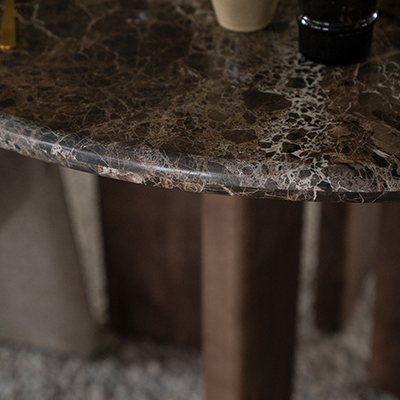 Mesa de comedor con sobre de mármol oscuro y patas de madera visibles