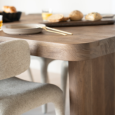 Mesa de comedor de madera natural en ángulo con pata clara y borde redondeado