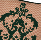 Cojín con bordado verde oscuro sobre tela con rayas naranjas