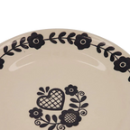 Plato llano crema con corazón negro y flores en el centro, diseño en el borde