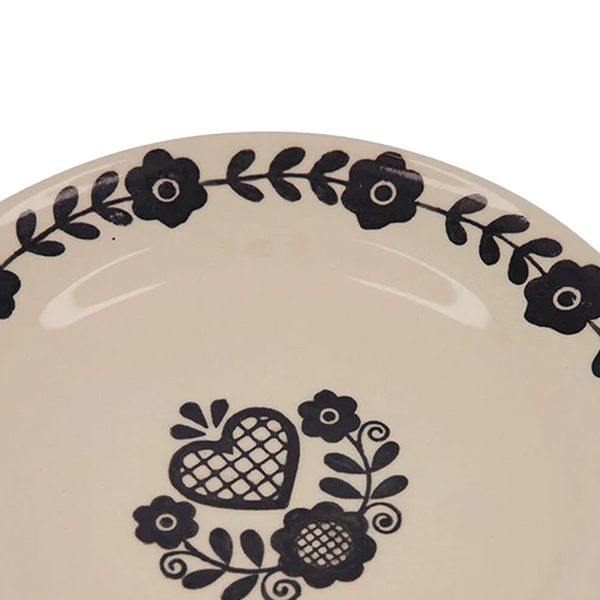 Plato llano crema con corazón negro y flores en el centro, diseño en el borde