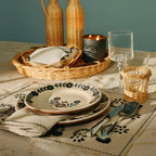 Set de individuales y servilleta beige con bordado negro floral, sobre mesa