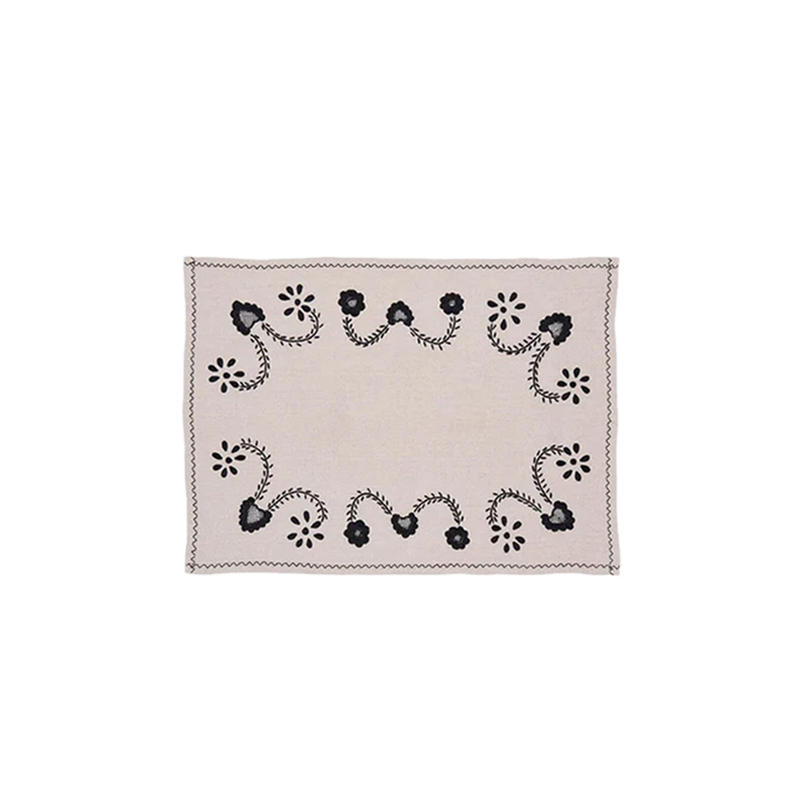 Individual beige con bordado negro floral y borde zigzag, pieza cuadrada