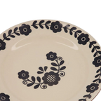 Plato de postre crema con flores y ramas negras en la parte superior