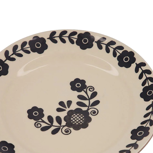 Plato de postre crema con flores y ramas negras en la parte superior