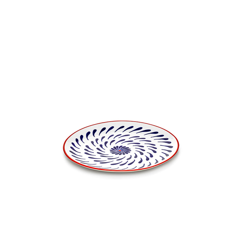 Plato llano con motivo espiral floral en azul y borde rojo, superficie blanca.