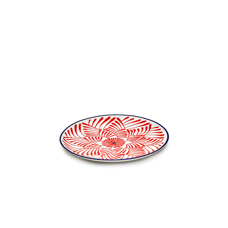 Plato llano rojo con flor geométrica y borde azul marino, superficie blanca.