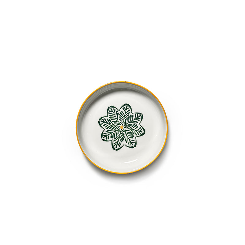 Plato cerámico blanco con borde amarillo y flor de hojas verdes al centro.