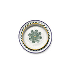 Plato cerámico blanco con borde amarillo y motivo verde sobre base azul con salpicaduras.