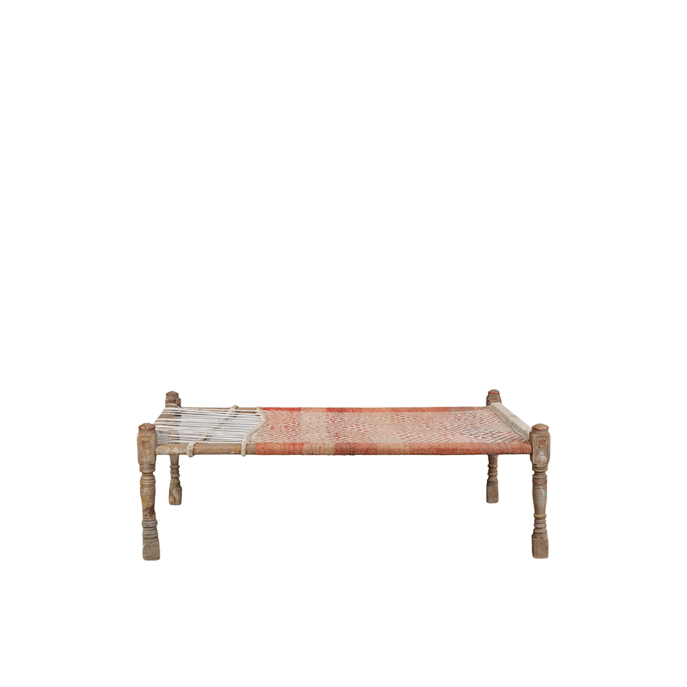 Cama charpai tradicional con tejido rojo y blanco y patas de madera tallada