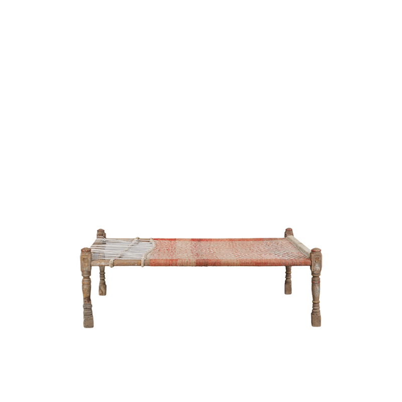Cama charpai tradicional con tejido rojo y blanco y patas de madera tallada