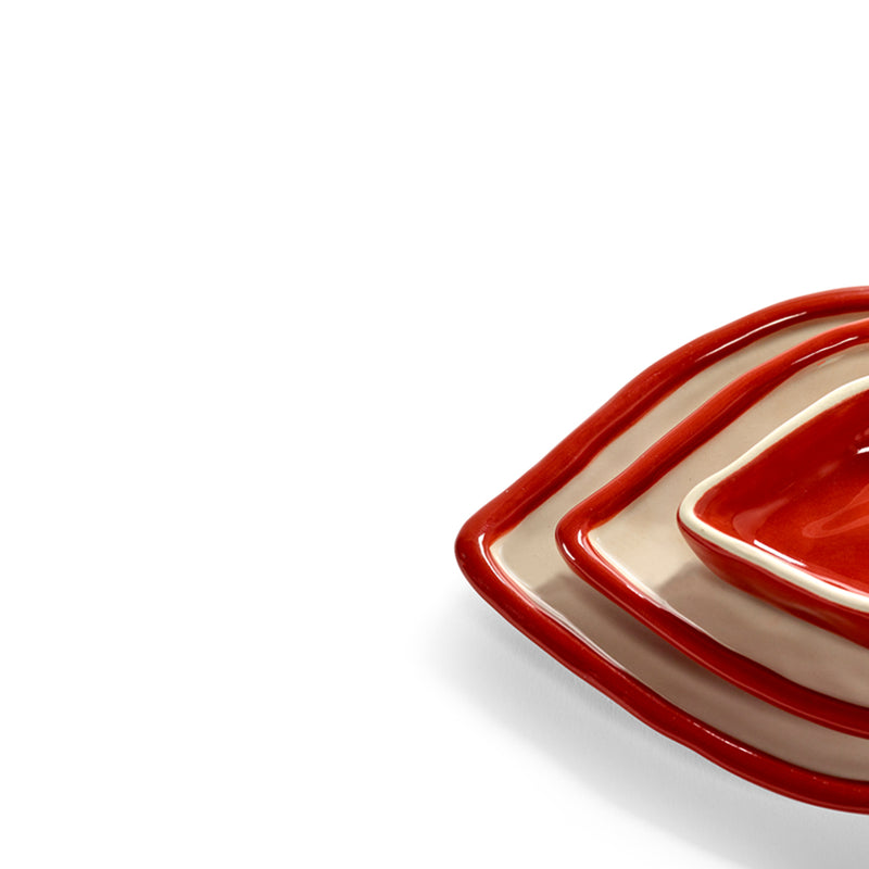 Detalle de bandeja decorativa con forma de labios, borde rojo y base beige