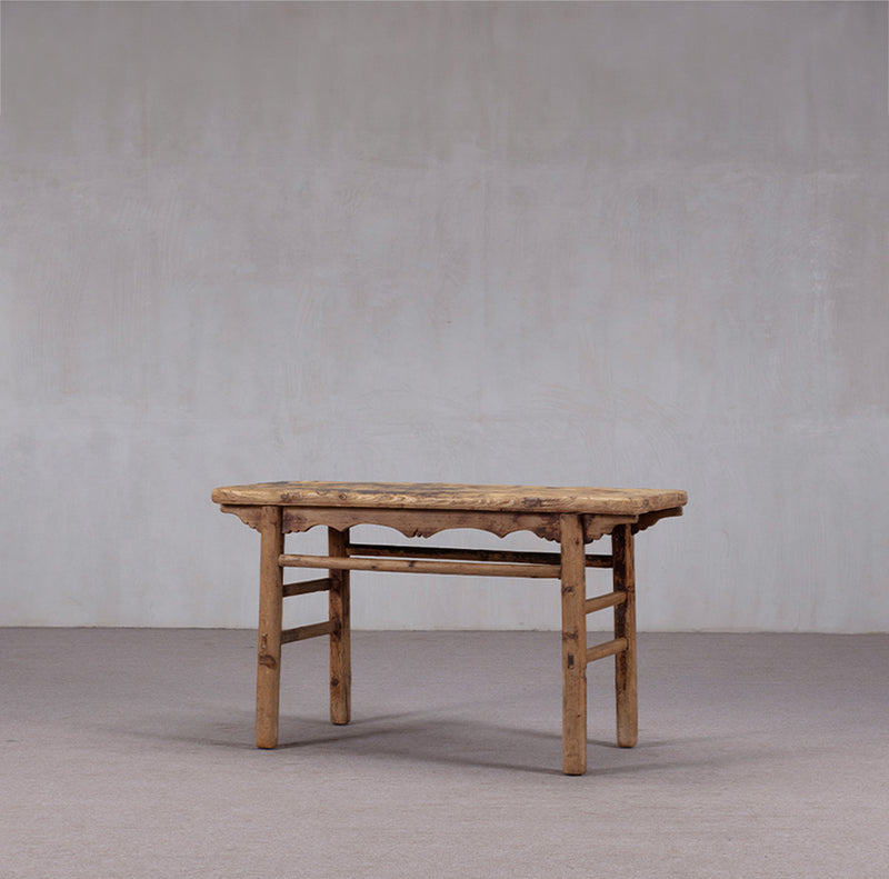 Consola antigua de madera con tablero rectangular y patas de madera, vista lateral con travesaños