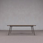 Mesa de comedor de madera con tablero rectangular oscuro y patas oblicuas de metal.