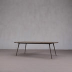 Mesa de comedor de madera con tablero rectangular y patas oblicuas; vista lateral.