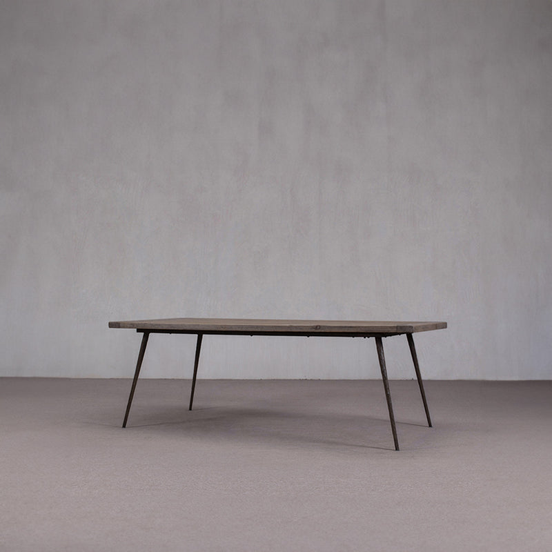 Mesa de comedor de madera con tablero rectangular y patas oblicuas; vista lateral.