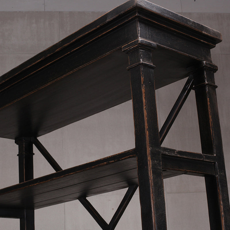 Detalle de librería alta de madera oscura: marco superior y montantes con cruces