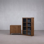 Vitrina alta de madera Heritage con puertas de vidrio, junto a mueble bajo de madera