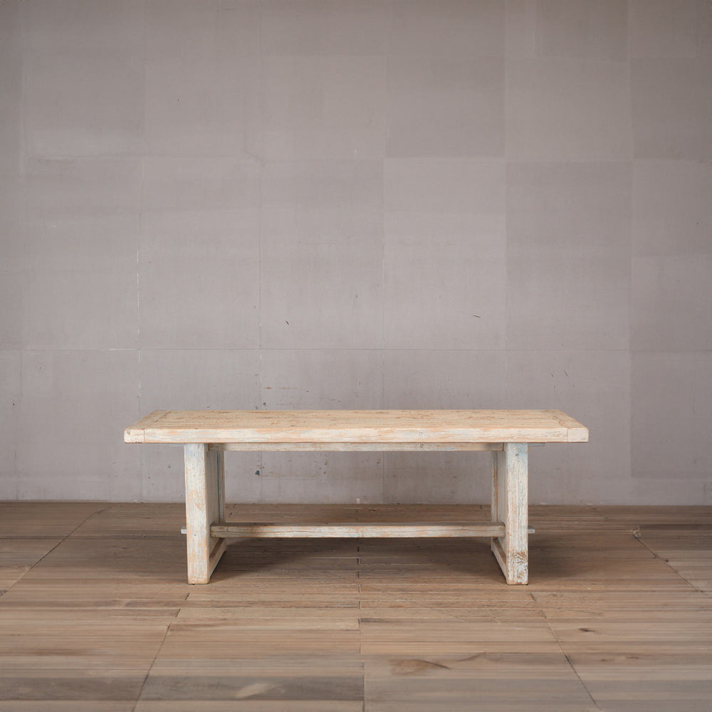 Mesa de comedor rectangular de madera clara de olmo con patas y acabado rústico.