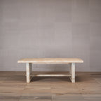 Mesa de comedor rectangular de madera clara de olmo con patas y acabado rústico.
