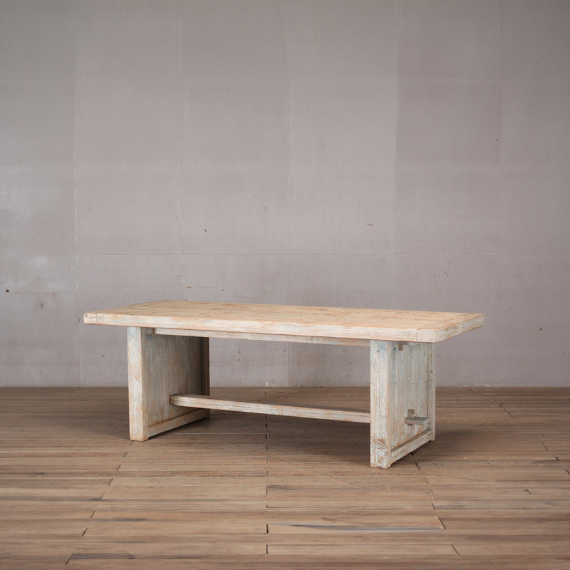 Mesa de comedor rectangular con travesaño inferior y acabado rústico en madera de olmo.