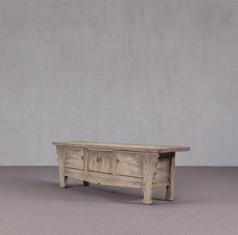 Mueble TV antiguo de madera desgastada con tres cajones y patas torneadas