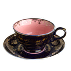 Taza de té con interior rosa y esmalte azul oscuro con motivos dorados y asa