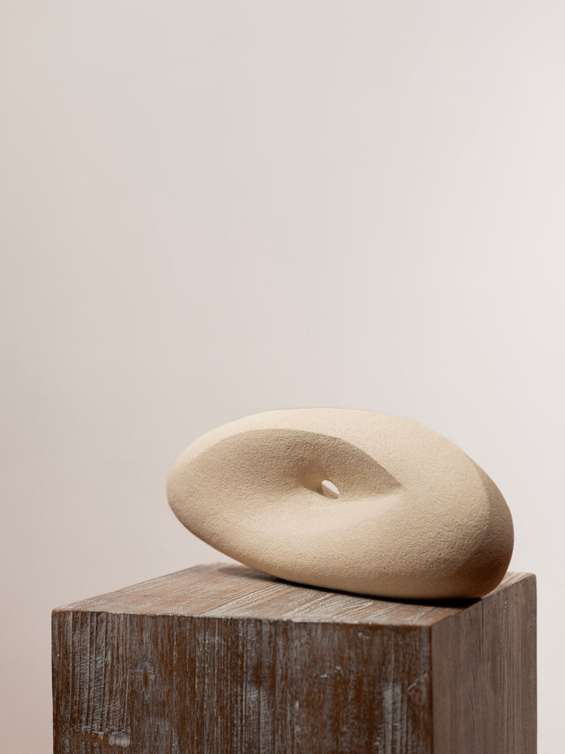 Escultura de gres cerámica beige: disco ovalado con ranura, apoyado en base de madera