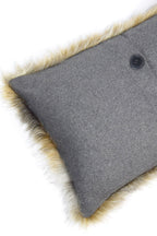 Cojín rectangular con esquina gris y botón negro, borde con pelo beige.