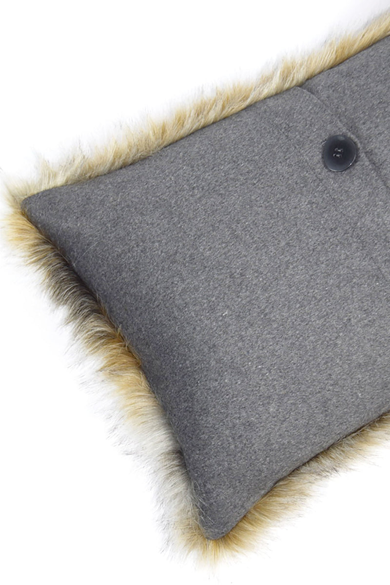 Cojín rectangular con esquina gris y botón negro, borde con pelo beige.