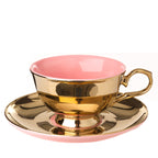 Taza de té con plato, interior rosado y exterior dorado con asa