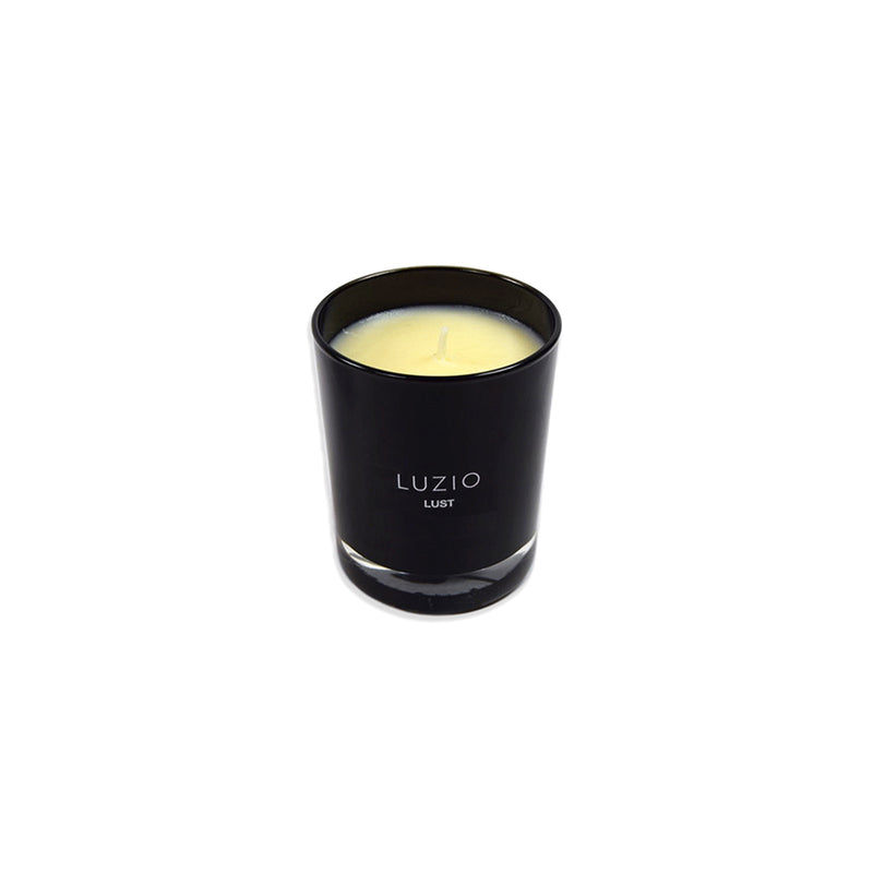 Vela en vaso negro LUZIO LUST encendida, con mecha central y cera amarilla