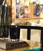Vela pequeña en vaso negro LUZIO LUST, con cera y etiqueta visible