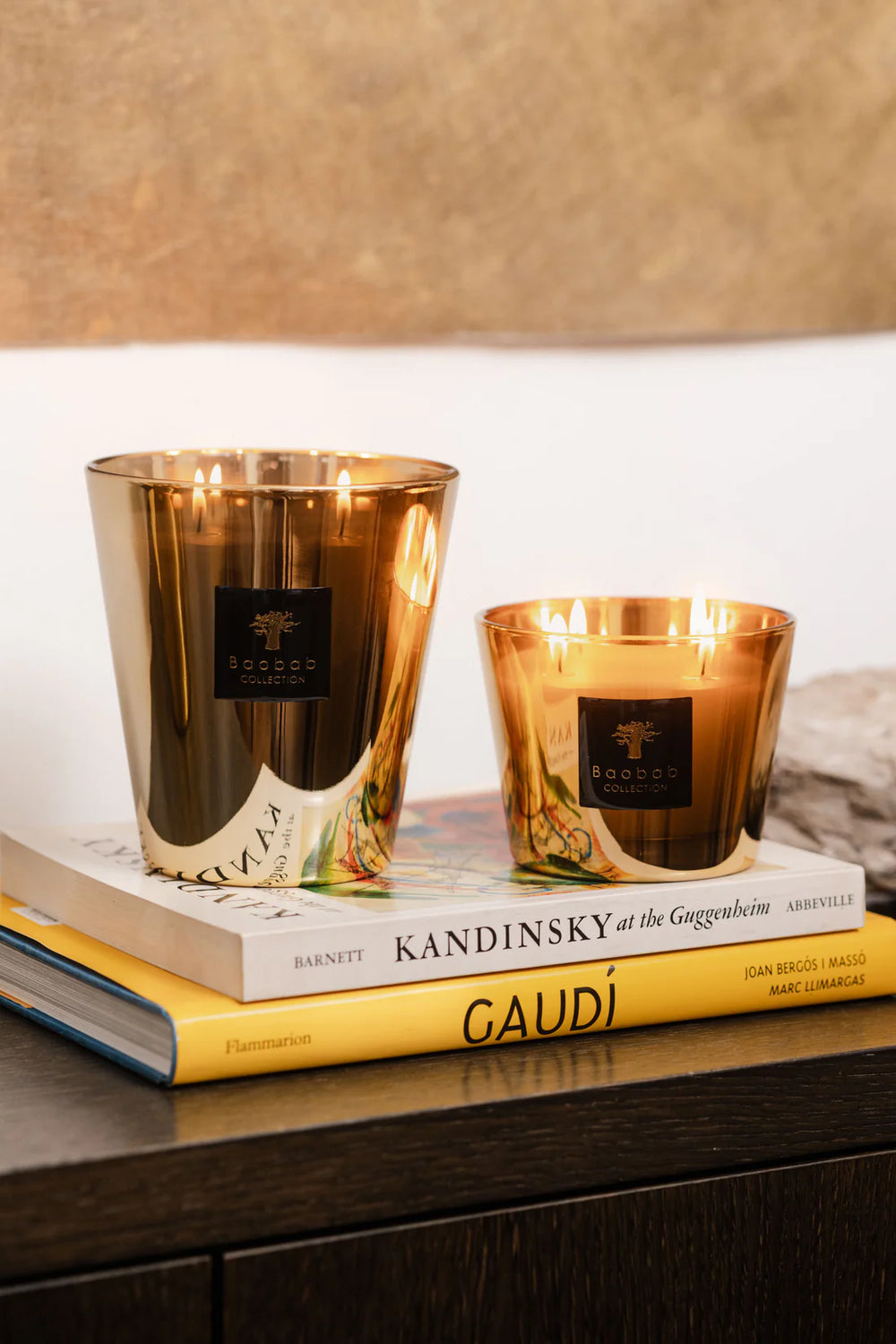 Par de velas en vasos de vidrio dorado con llamas y etiqueta Baobab.