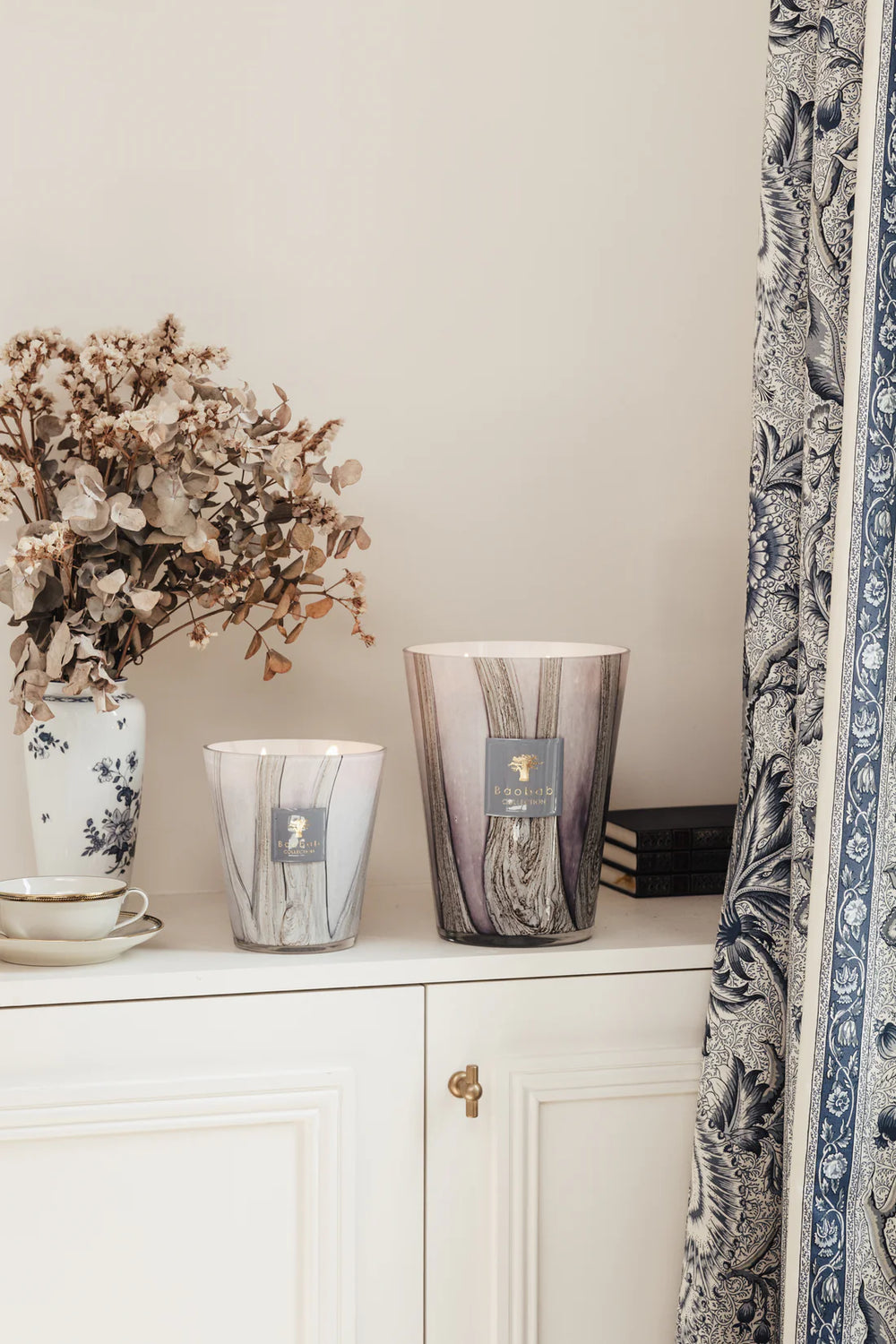 Vela en vaso de vidrio transparente con vetas grises y etiqueta azul Baobab Collection