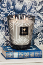 Vela encendida en vaso de vidrio ahumado con patrón blanco y etiqueta Baobab Collection