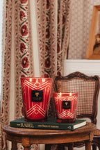 Par de velas en vasos rojos con líneas blancas y etiquetas Baobab Collection, encendidas