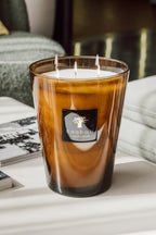 Vela Baobab en vaso de vidrio ámbar con varias mechas encendidas y etiqueta negra