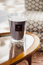 Vela en vaso de vidrio con cera morada y mechas encendidas, etiqueta Baobab