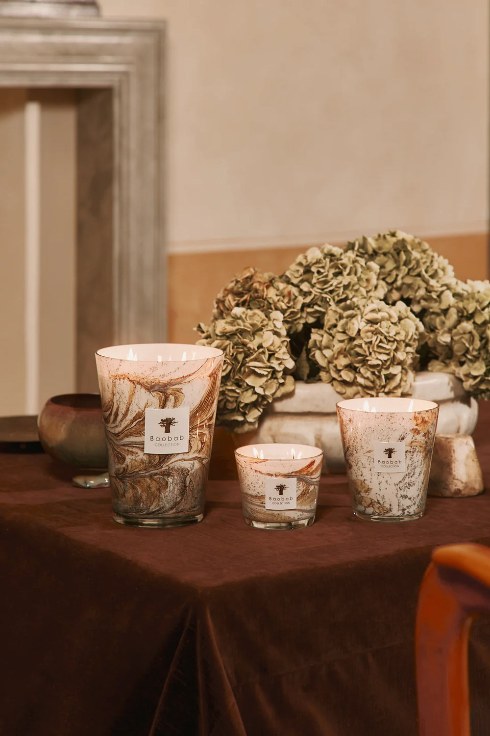 Vela en vaso de vidrio con etiqueta y diseño marmoleado, con llama encendida