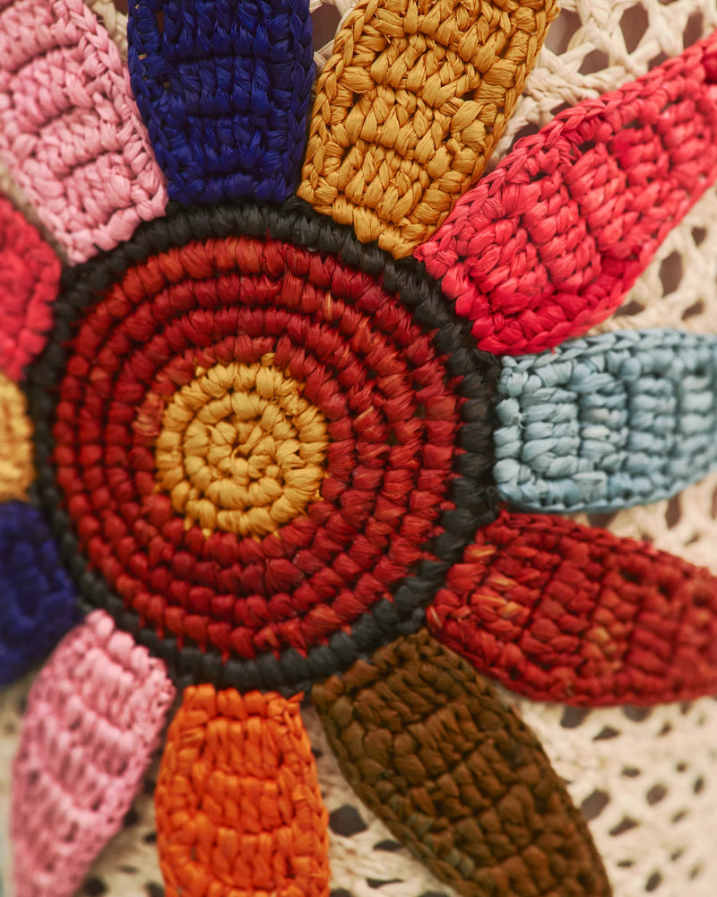 Vela con flor bordada artesanal en tonos rojo, naranja, azul y amarillo sobre malla beige