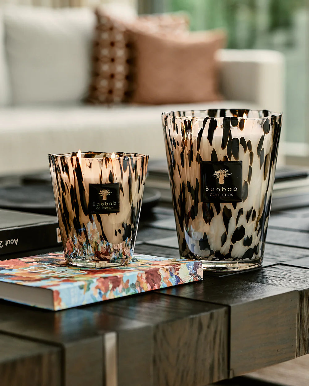 Vela en vaso de vidrio con estampado negro y dorado, etiqueta Baobab en el centro.