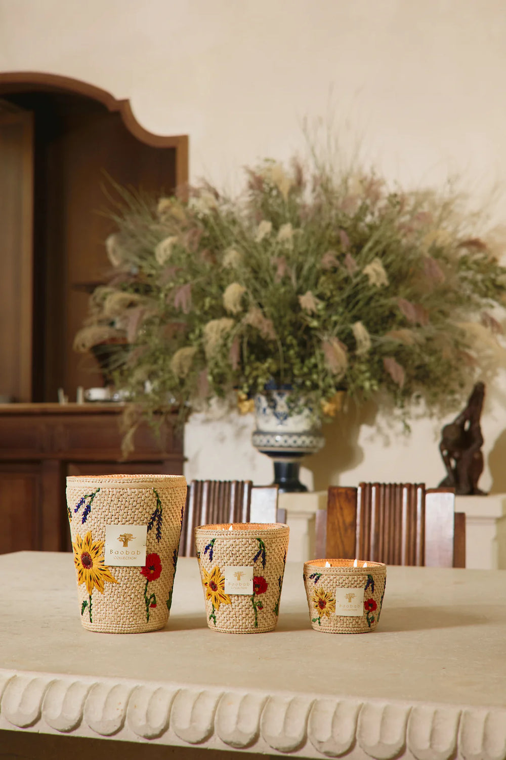 Set de velas en frascos de fibra tejida con estampado floral, sobre mesa