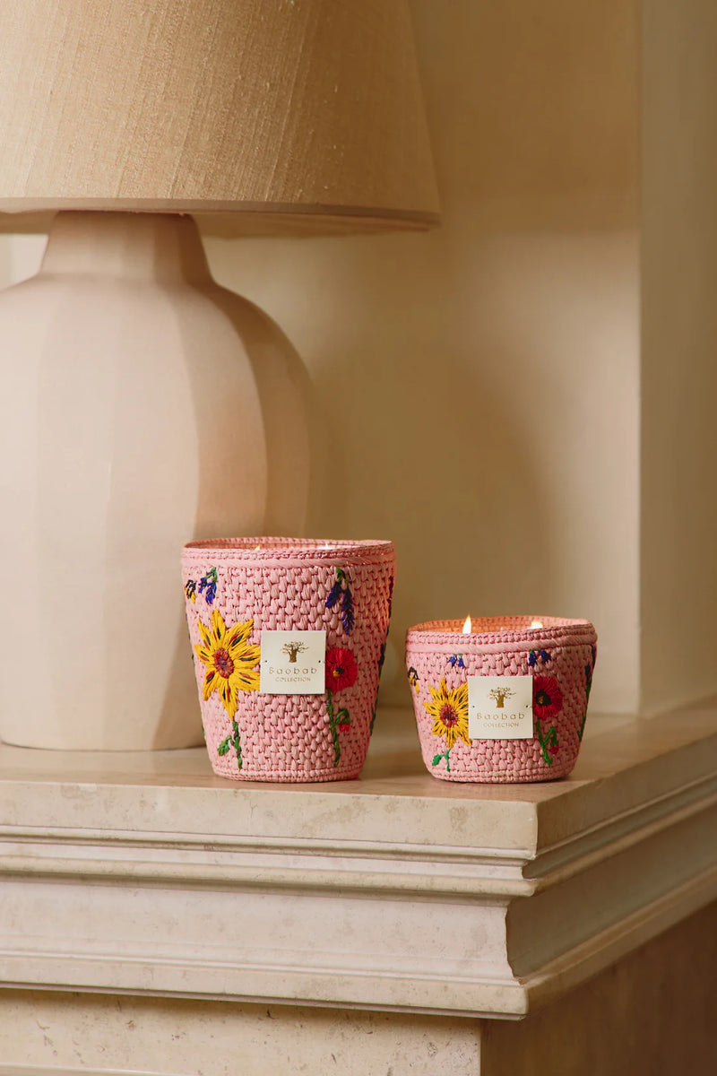 Vela Baobab en recipiente trenzado rosa con flores bordadas y etiqueta blanca; dos tamaños.
