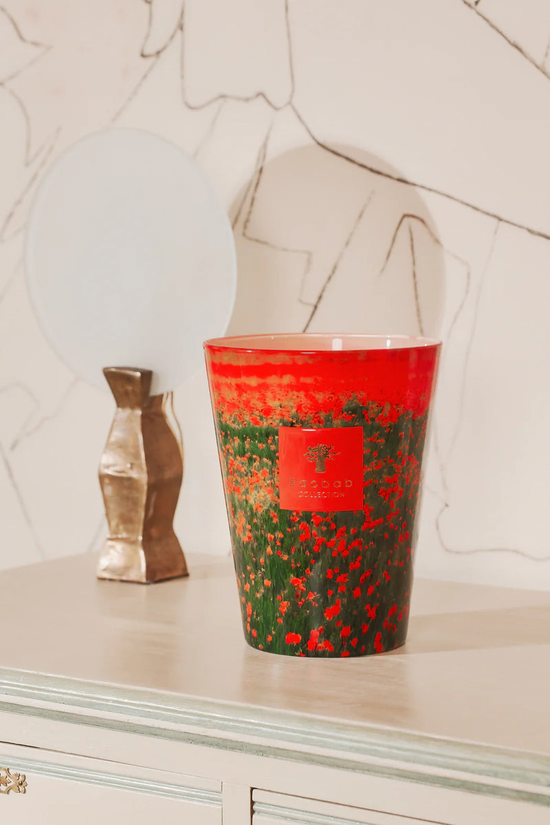 Vela Baobab en vaso rojo y verde con flores, etiqueta Baobab Collection en el centro