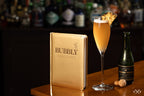 Libro Bubbly de portada dorada junto a copa de bebida espumosa