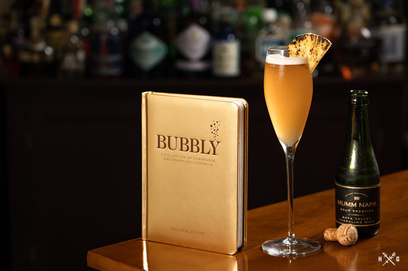 Libro Bubbly de portada dorada junto a copa de bebida espumosa